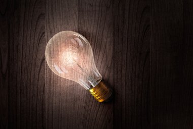 Ahşap yüzey üzerinde ampul. Karışık teknik