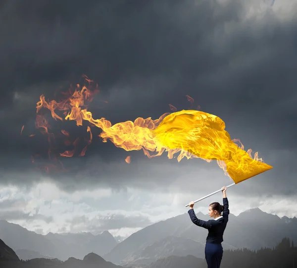 Woman waving yellow flag . Mixed media — Stock Photo, Image