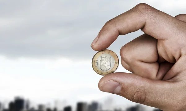 Five euro coin between fingers . Mixed media — Stock Photo, Image