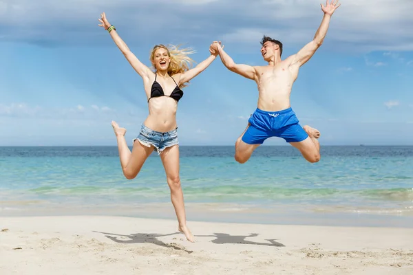 Joyeux couple sautant en vacances à la plage — Photo