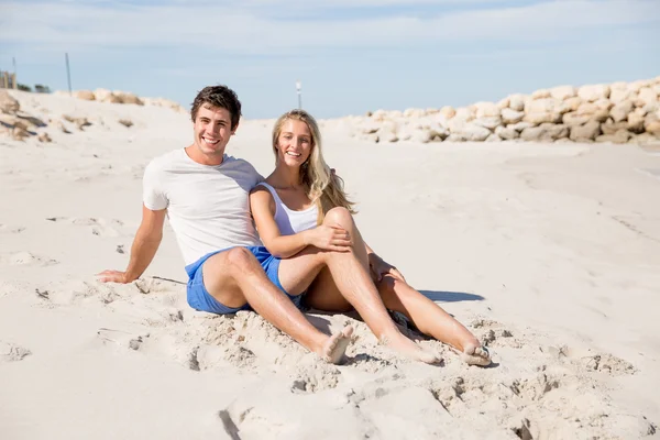 Romantiska unga paret sitter på stranden — Stockfoto