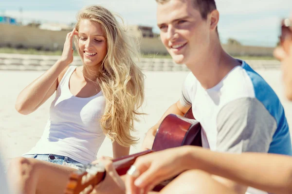 Jovens bonitos com guitarra na praia — Fotografia de Stock