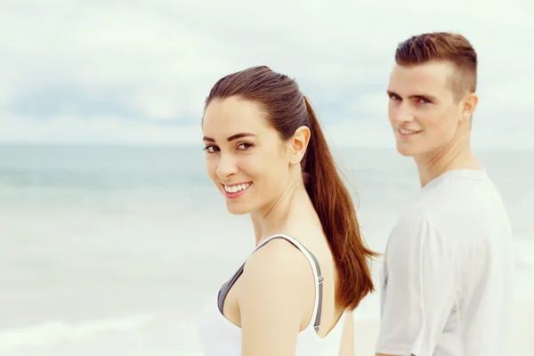 Jong koppel op zoek naar camera terwijl staande naast elkaar op het strand — Stockfoto