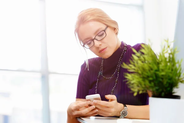 Zakenvrouw in kantoor houden van mobiele telefoon — Stockfoto