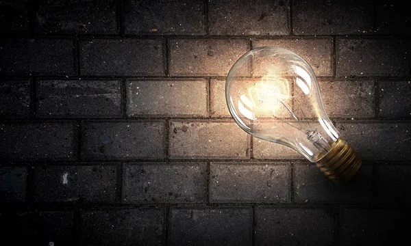 Light bulb op baksteen oppervlak — Stockfoto