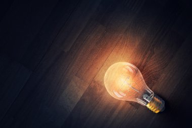 Ahşap yüzey üzerinde ampul. Karışık teknik