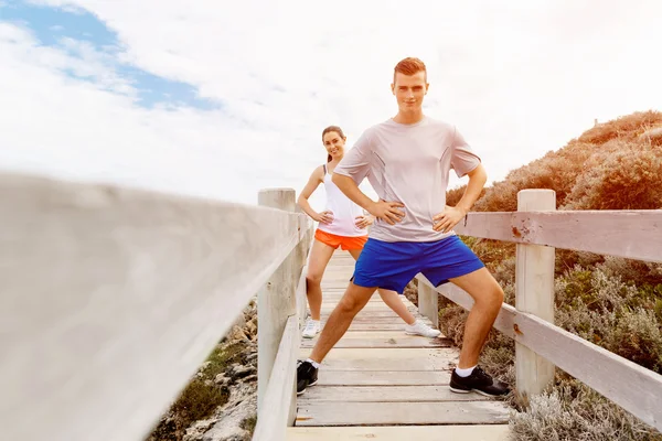 Corredores. Pareja joven haciendo ejercicio y esteretizando en la playa —  Fotos de Stock