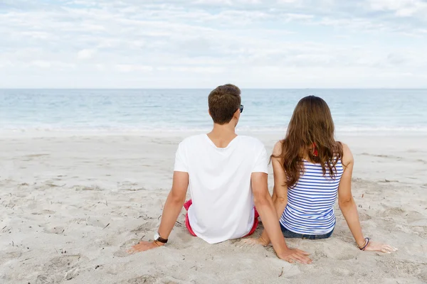 Romantique jeune couple assis sur la plage — Photo