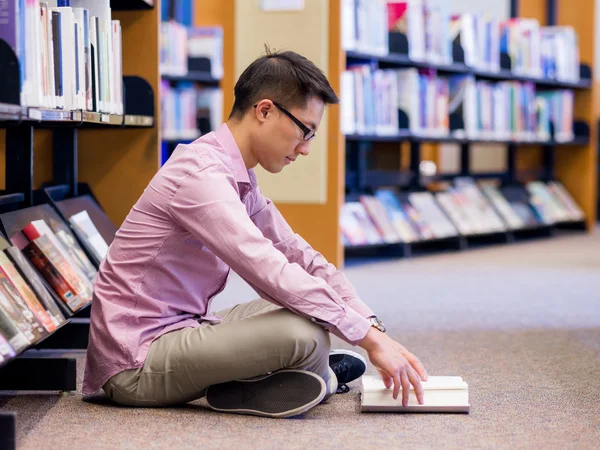 Glücklicher männlicher Student mit Büchern in der Bibliothek — Stockfoto