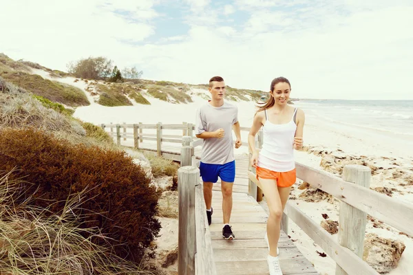 Des coureurs. Jeune couple courant sur la plage — Photo