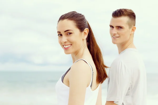 Young couple looking at camera while standing next to each other on beach — Stock Photo, Image