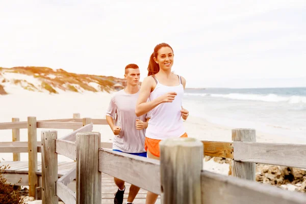 Des coureurs. Jeune couple courant sur la plage — Photo