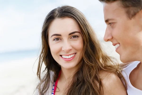 Romantische jonge paar zittend op het strand — Stockfoto