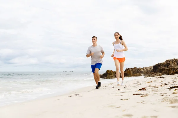 Des coureurs. Jeune couple courant sur la plage — Photo