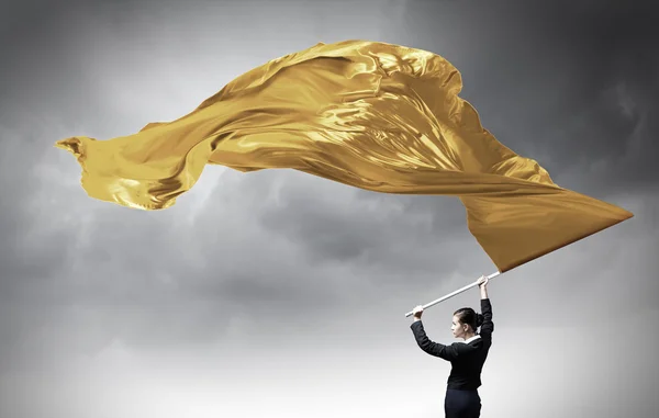 Woman waving yellow flag . Mixed media — Stock Photo, Image