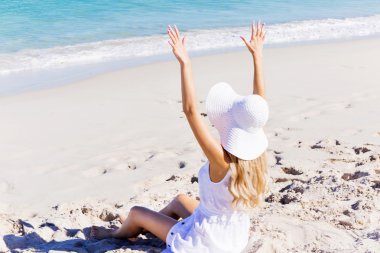 Genç bir kadın sahilde dinleniyor.