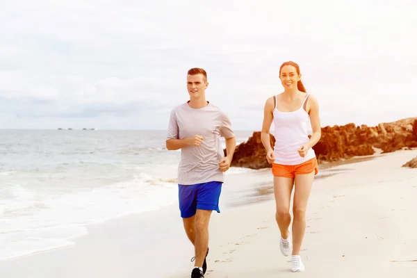 Des coureurs. Jeune couple courant sur la plage — Photo