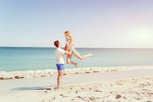 Casal feliz pulando em férias na praia — Fotografia de Stock