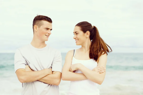 Young couple looking at each other while standing on beach — Stock Photo, Image