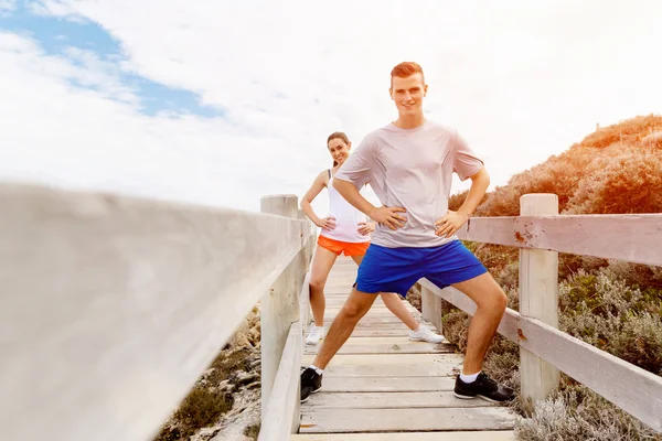 Des coureurs. Jeune couple exerçant et stertching sur la plage — Photo