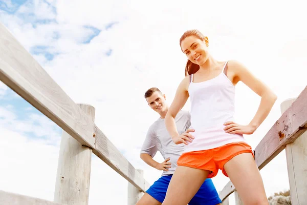 Corredores. Pareja joven haciendo ejercicio y esteretizando en la playa —  Fotos de Stock