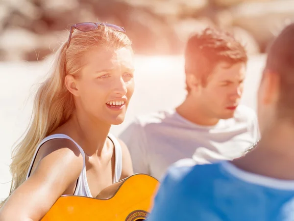 美丽的年轻女子在海滩上弹奏吉他 — 图库照片