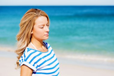 Genç bir kadın sahilde dinleniyor.