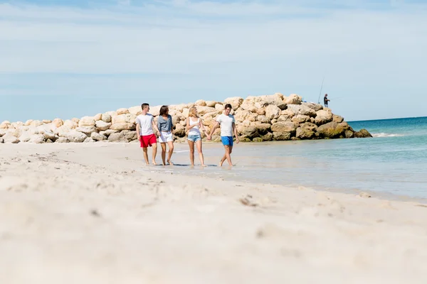 Företag av unga människor på stranden — Stockfoto