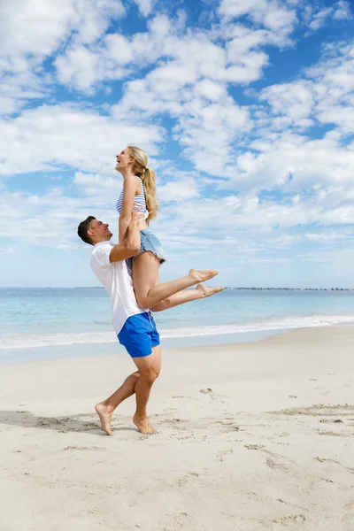 Casal feliz pulando em férias na praia — Fotografia de Stock