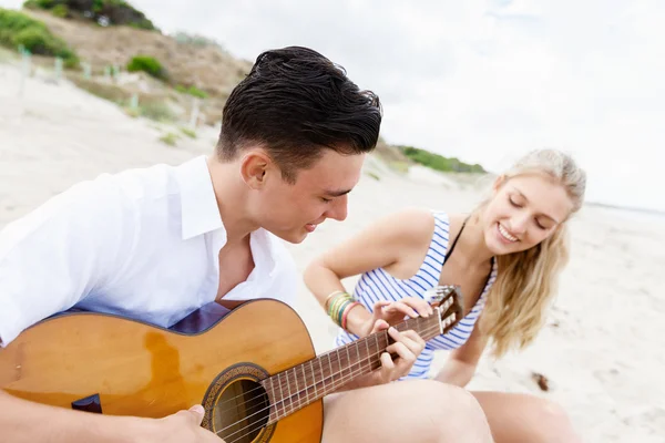 Young couple playing guitar on beach in love