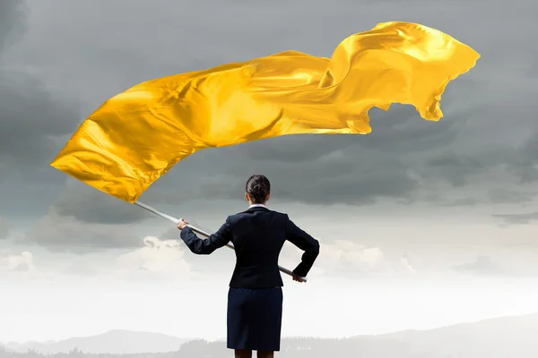 Woman waving yellow flag . Mixed media — Stock Photo, Image