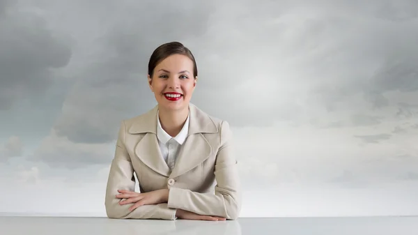 Businesswoman sitting at desk . Mixed media — Stock Photo, Image