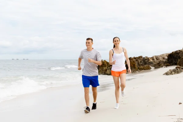 Des coureurs. Jeune couple courant sur la plage — Photo