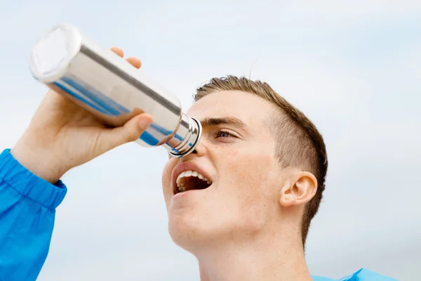 Чоловік п'є зі спортивної пляшки — стокове фото