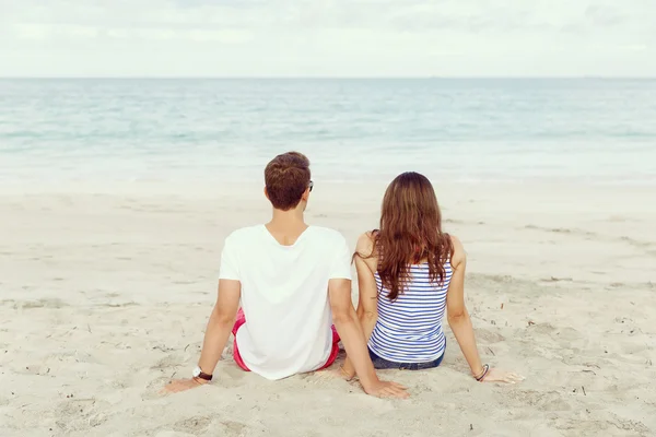 Romántica pareja joven sentada en la playa — Foto de Stock