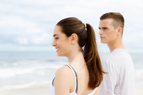 Mladý pár zamyšleného stoje vedle sebe na pláži — Stock fotografie