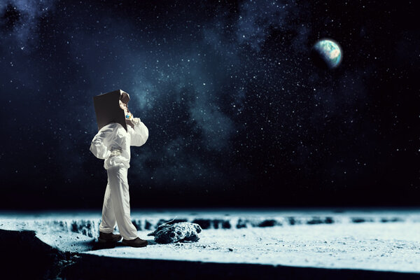Young woman with carton box on head imagine she is astronaut. Elements of this image are furnished by NASA