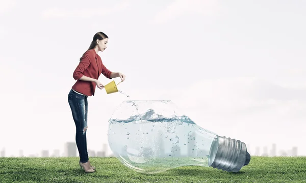 Girl pouring water from bucket . Mixed media — Stock Photo, Image