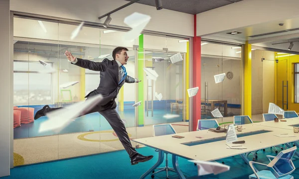 Jumping businessman in office . Mixed media — Stock Photo, Image