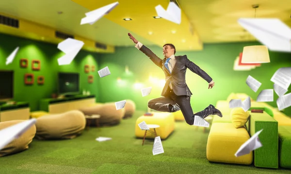 Jumping businessman in office . Mixed media — Stock Photo, Image