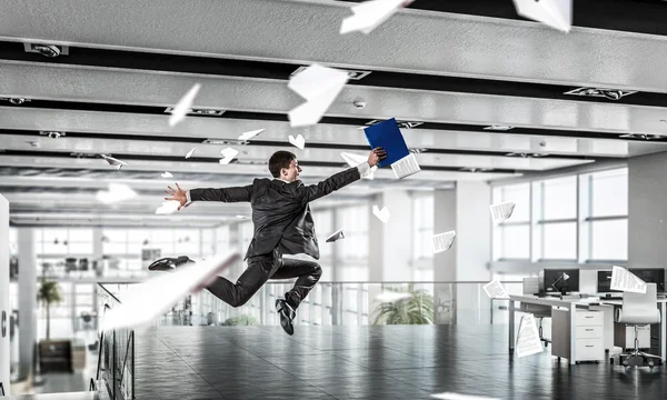 Jumping businessman in office . Mixed media — Stock Photo, Image