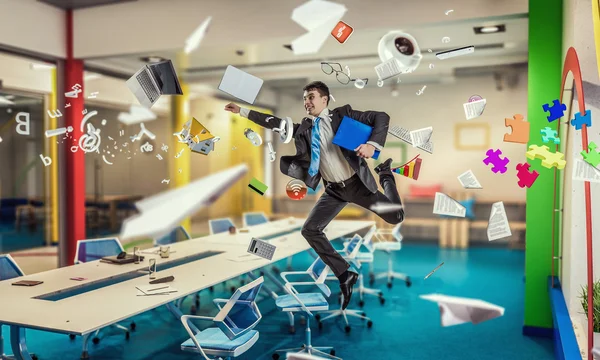 Jumping businessman in office . Mixed media — Stock Photo, Image