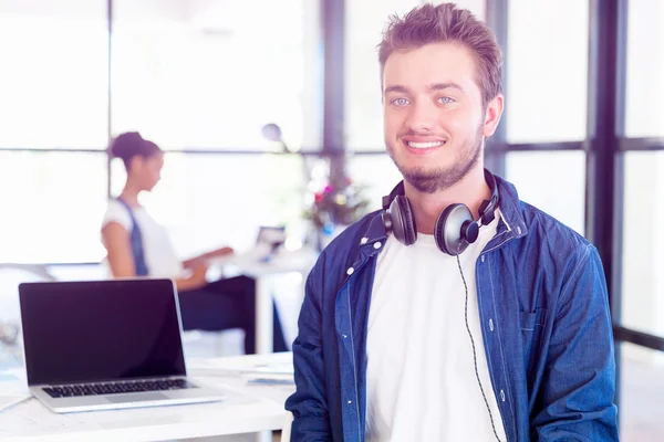 Junger Mann sitzt im Büro und schaut in die Kamera — Stockfoto