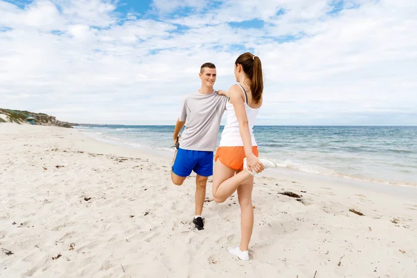 Lopers. Jong koppel uit te oefenen en stertching op strand — Stockfoto