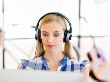 Kulaklıklar ile ofiste çalışan genç kadın