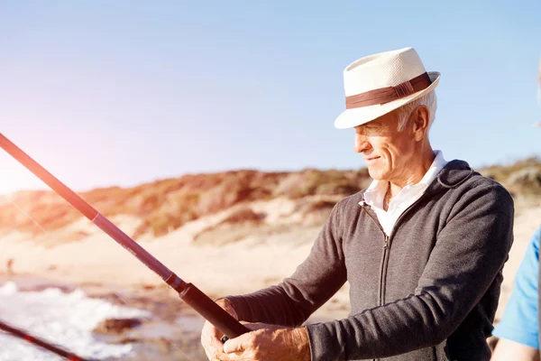 Senior man fishing at sea side — Stock Photo, Image