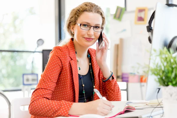 Ung kvinna med mobiltelefon i office — Stockfoto