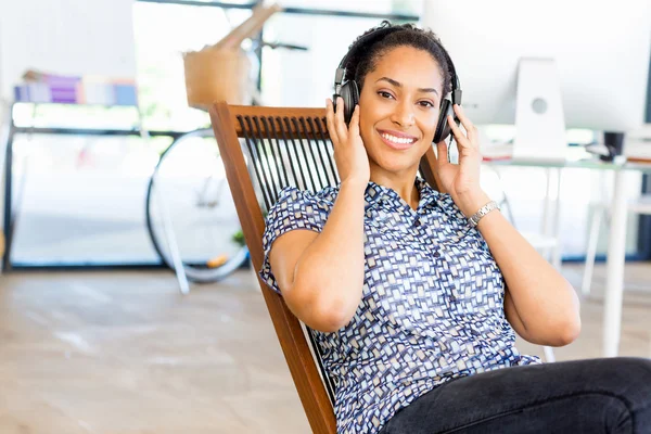 Porträtt av leende afro-american kontorsarbetare sitter i offfice med hörlurar — Stockfoto