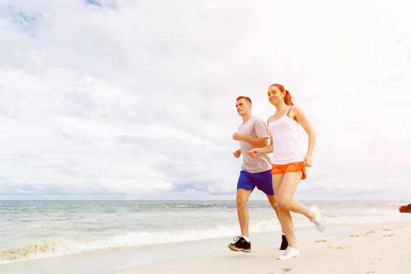 Löpare. Ungt par körs på stranden — Stockfoto