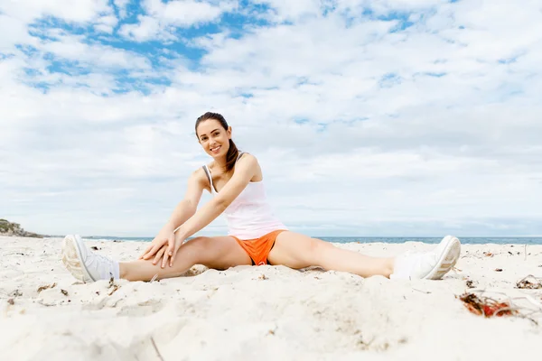 Mujer joven entrenando en la playa afuera — Foto de Stock